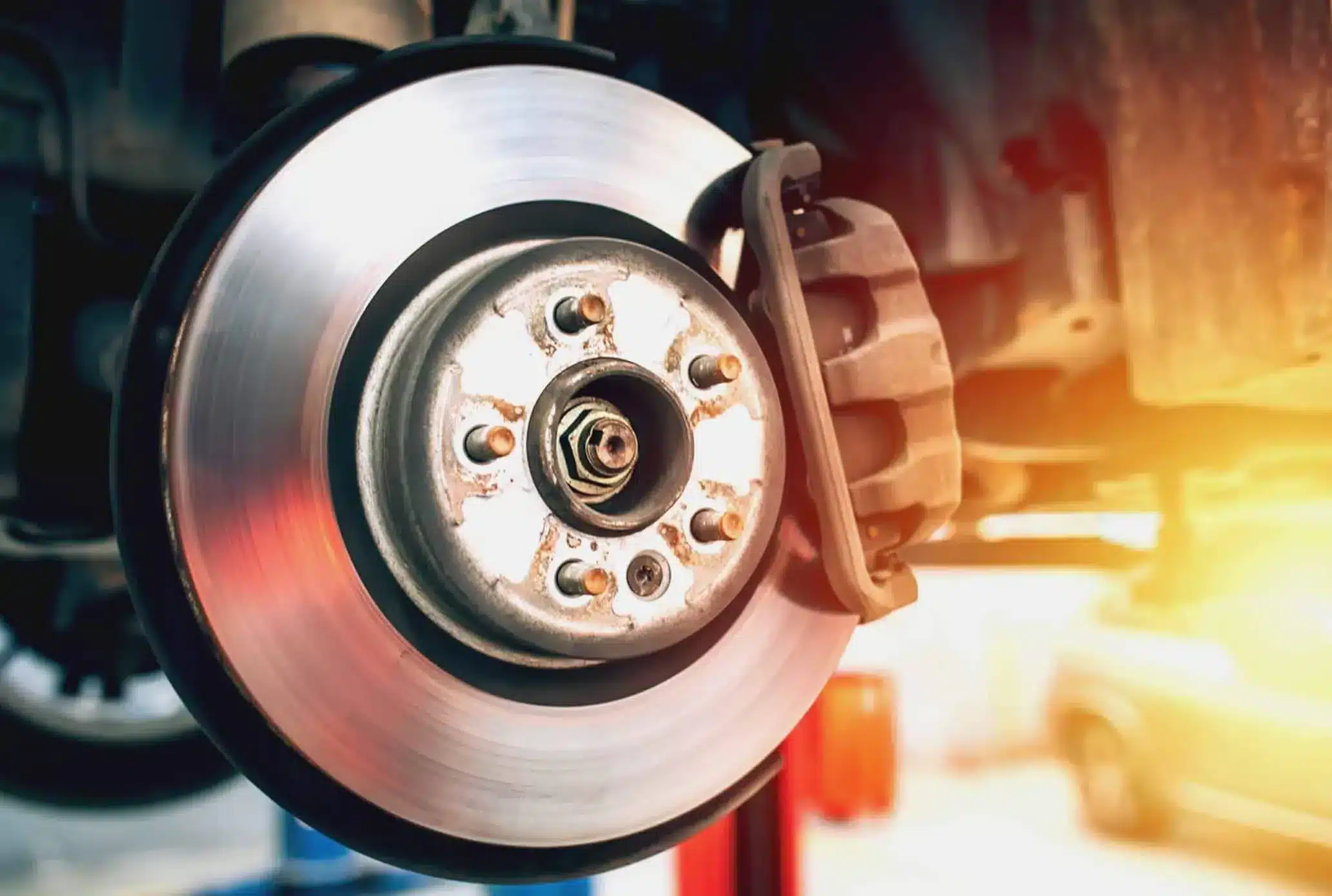 Close-up of brake calipers and pads being examined during service.