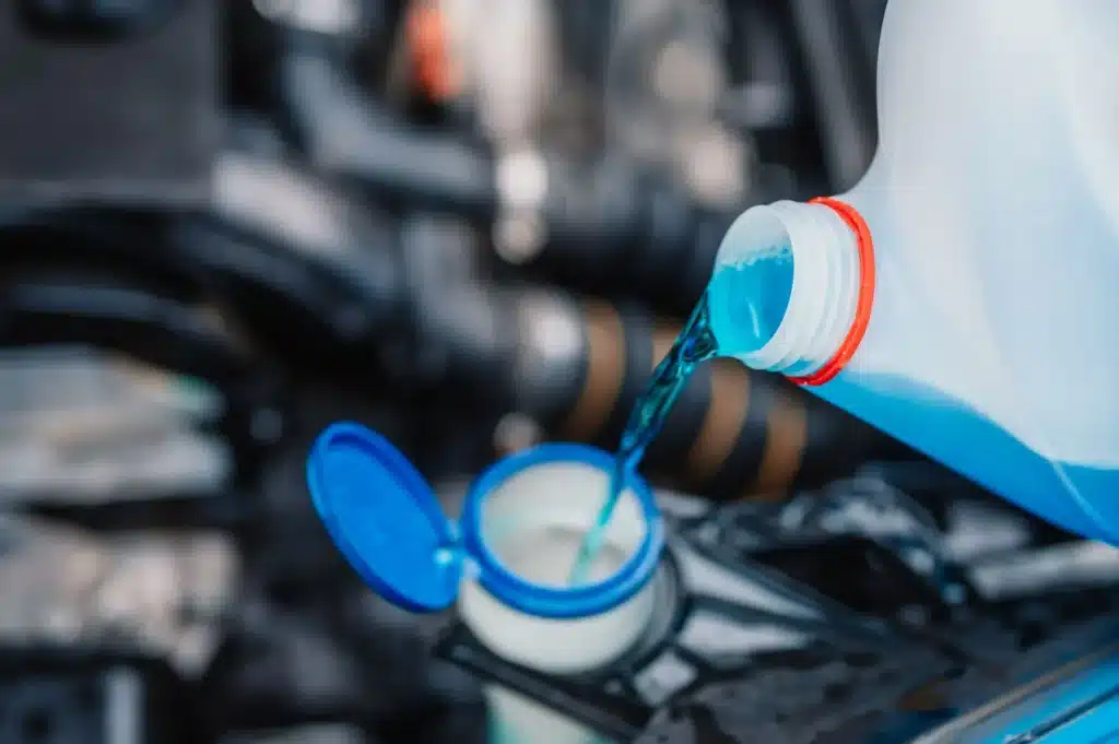 Close-up of coolant being poured into the radiator during vehicle maintenance.