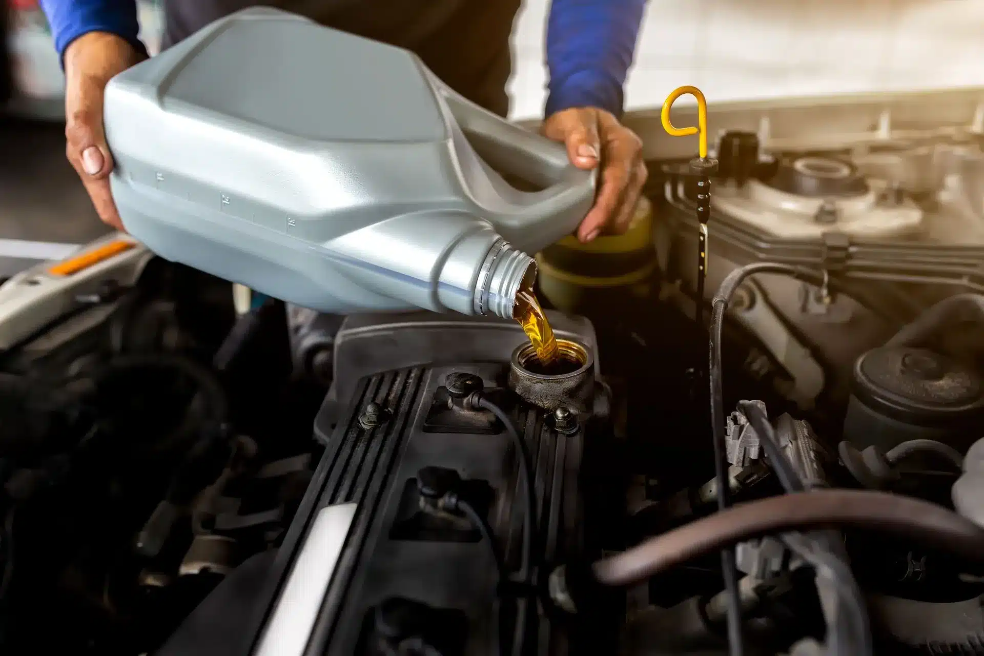 Close-up of engine oil being added to the engine compartment during an oil change.