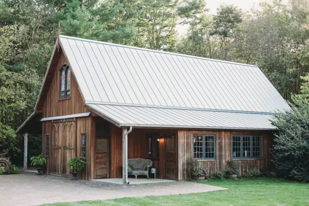 Small wooden building with a corrugated metal roof, nestled among trees.