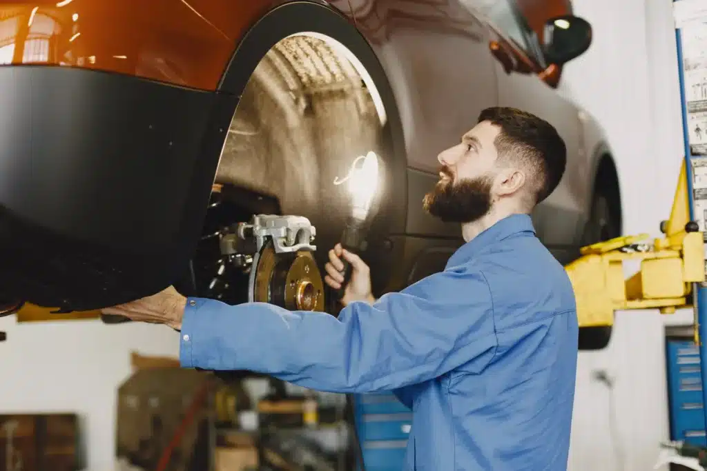 Technician performing maintenance on a vehicle's brake system and performing brake inspection.