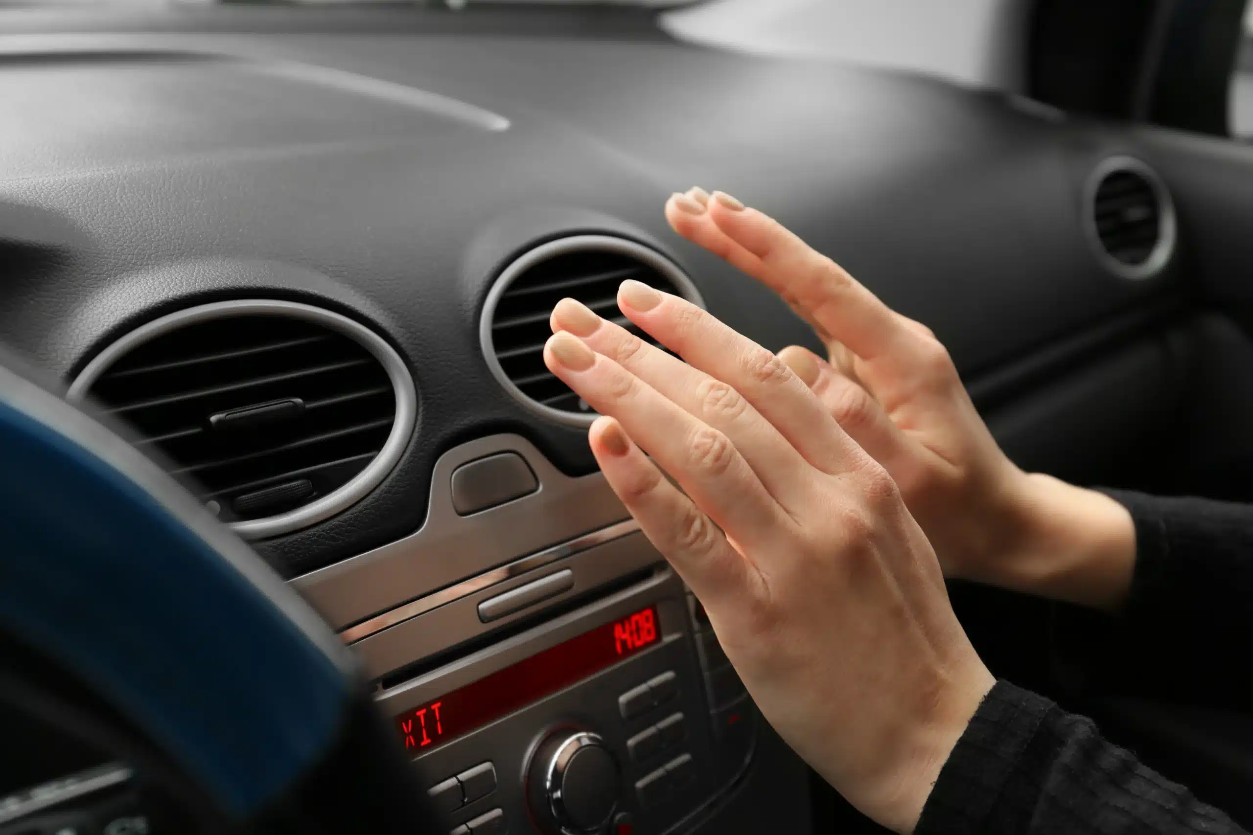 Auto AC Repair in Floyds Knobs, IN by Schindler’s Garage. Image of a woman checking the car air ventilation to understand why it is blowing hot air, indicating that the car needs to go to the AC repair shop