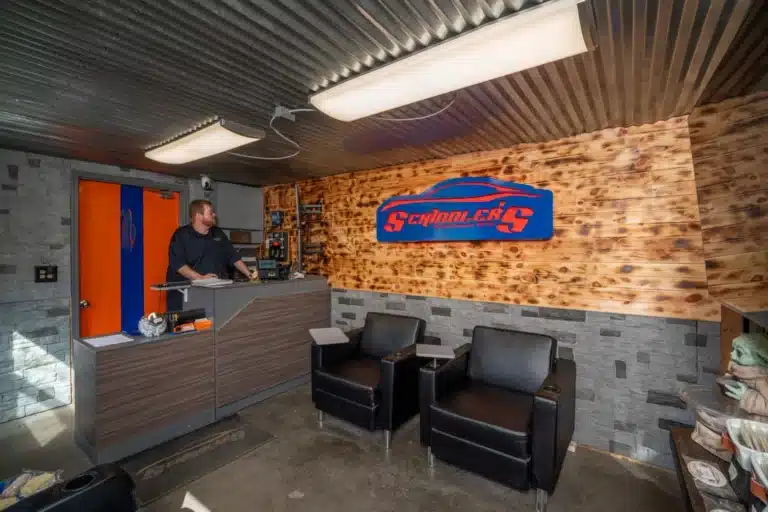 Wide view of the reception area at Schindler's Garage, featuring a welcoming and organized space with seating, reception desk, and logo signage.