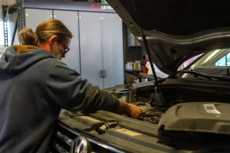 Classic car technician inspecting the engine bay for potential issues at Schindler's Garage, ensuring thorough diagnostics and maintenance.