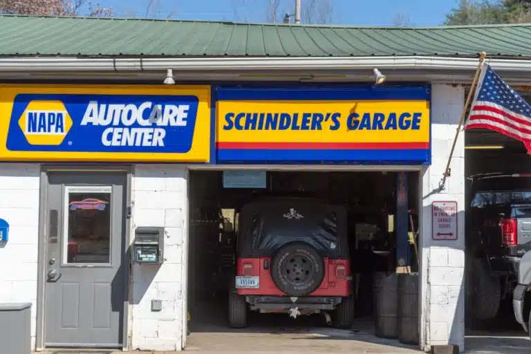 Panoramic view of the exterior of Schindler's Garage, showing the front of the building with its distinctive signage, surrounded by a parking area and surroundings.