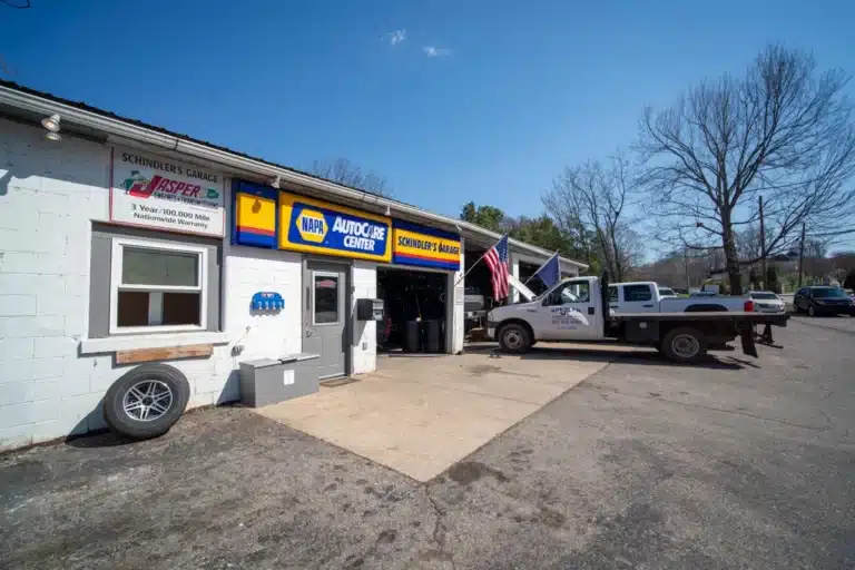 Panoramic view of the exterior of Schindler's Garage, showing the front of the building with its distinctive signage, surrounded by a parking area and landscaped surroundings.