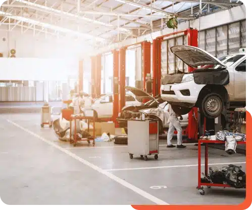 A modern auto repair shop with multiple car lifts, open hoods, and various tools and equipment, showcasing a well-lit and organized workspace with technicians working on vehicles.