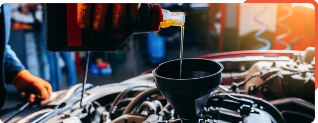 Close-up of fresh oil being poured into the engine during maintenance at Schindler's Garage