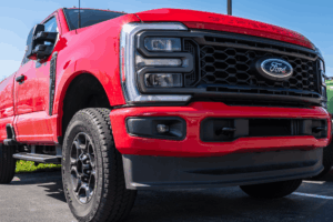 Ford services, auto repair in Floyds Knob, IN by Schindler's Garage. Image of a bright red Ford Super Duty pickup parked outside, showcasing the grille, heavy-duty tires, and rugged build ready for service.