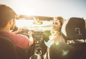 Summer Maintenance for your ford by Schindler's Garage in Floyds Knobs, IN: A couple enjoying a road trip in a convertible, driving down a sunny road, illustrating the importance of summer car maintenance for a smooth journey.