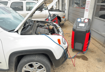 ac check, auto repair in Floyds Knobs, IN at Schindler's Garage. Car undergoing air conditioning service with a Snap-on refrigerant recovery machine connected under the hood at an auto repair shop.