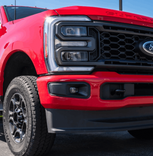 Ford services, auto repair in Floyds Knob, IN by Schindler's Garage. Image of a bright red Ford Super Duty pickup parked outside, showcasing the grille, heavy-duty tires, and rugged build ready for service.