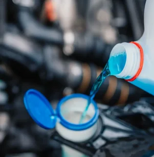 Close-up of coolant being poured into the radiator during vehicle maintenance.