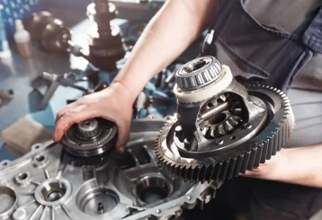 Close-up of a mechanic inspecting transmission components of a vehicle at Schindler's Garage.